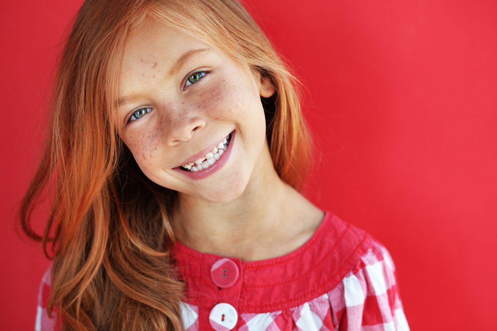 Cute redheaded child on red background