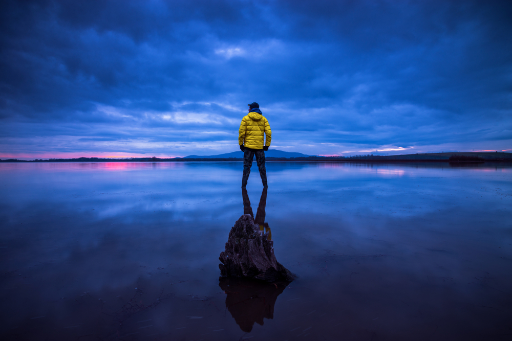 Man in a yellow jacket at the ocean during blue hour