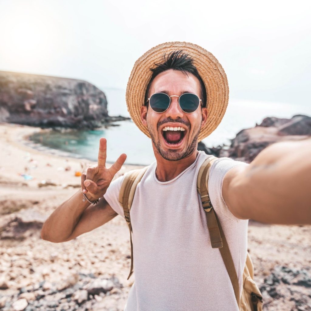 Man in straw hat giving peace sign taking a selfie. Example of 1:1 aspect ratio.