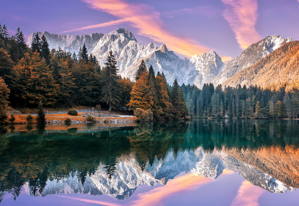 Impressive Autumn landscape during sunset. The Fusine Lake in front of the Mongart under sunlight. Amazing sunny day on the mountain lake.