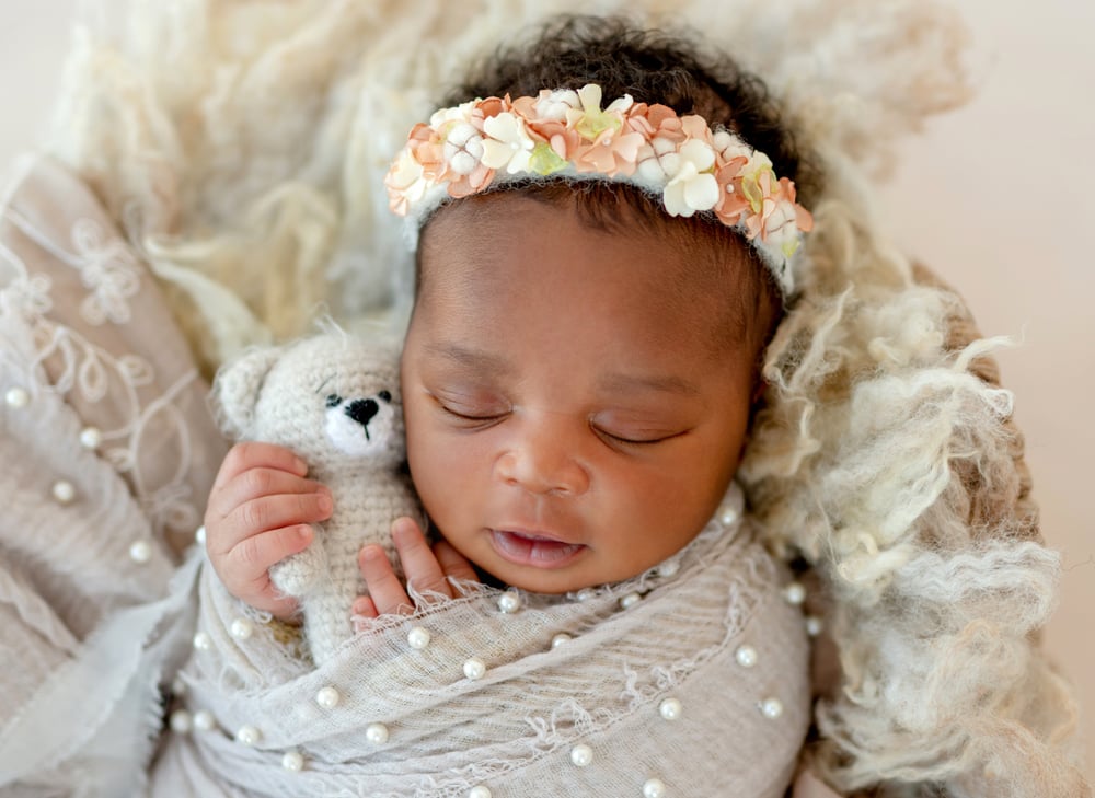 New born baby girl with flower crown and teddy bear