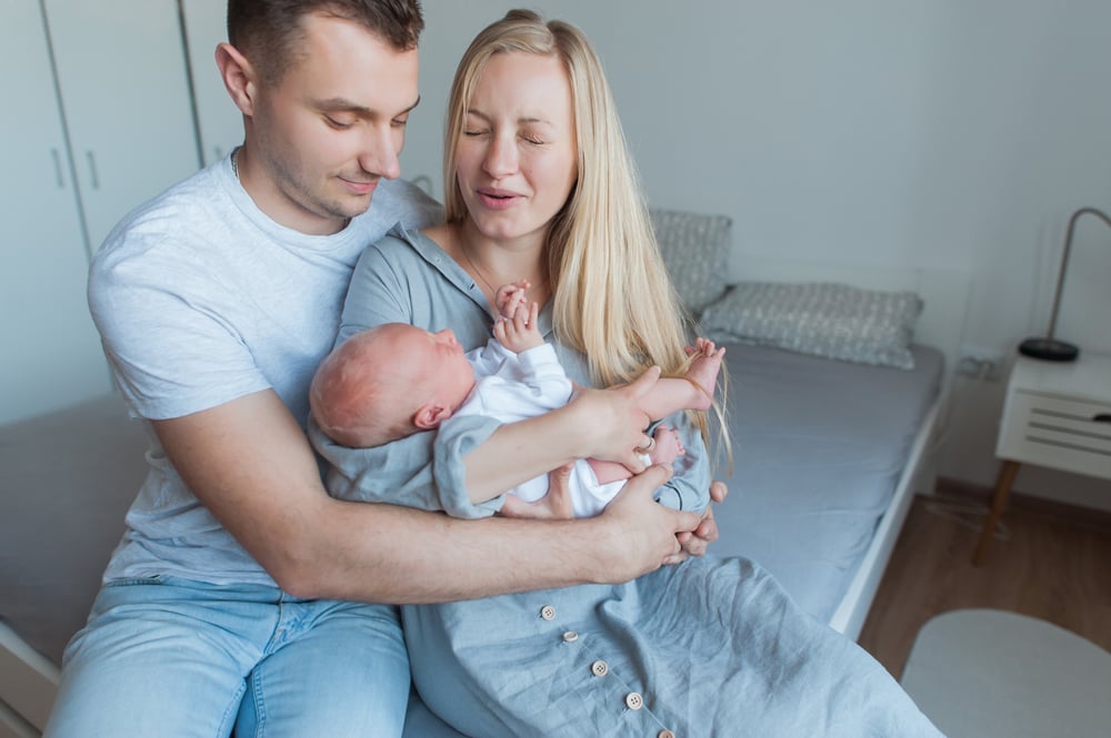 Newborn baby with parents on a bed