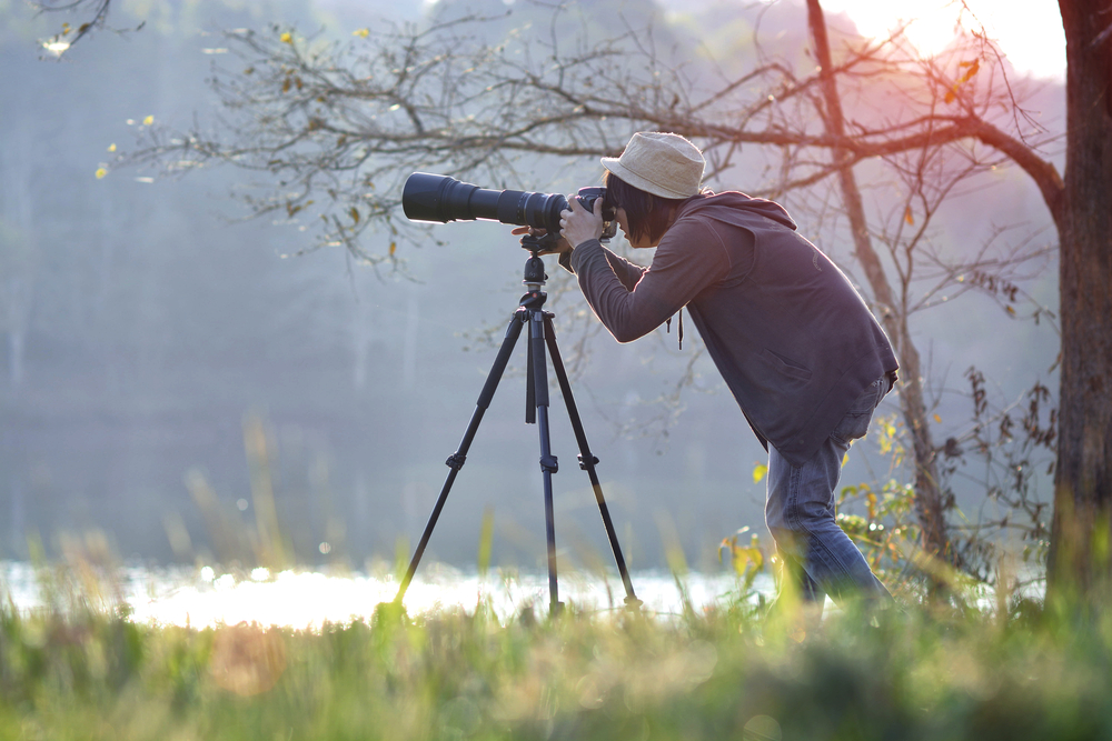 Photographer using a telephoto lens and tripod