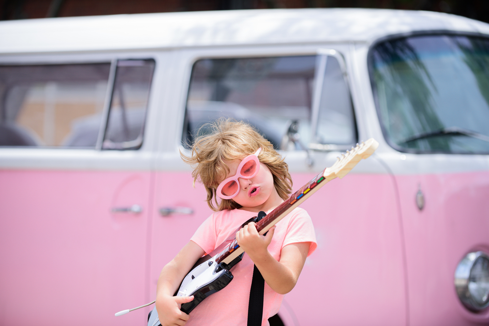 a funny child with pink glasses paying guitar