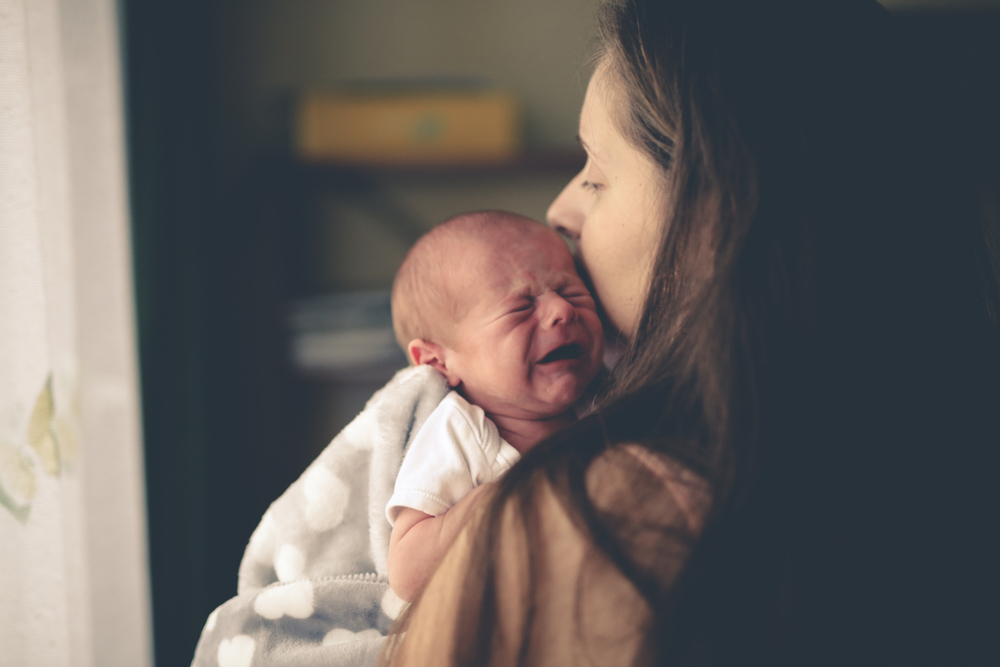 crying newborn baby with mom