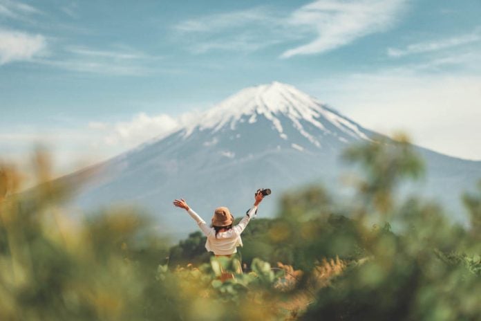 Happy tourist traveler woman enjoying with open arms on lake kawaguchiko with mount fuji in japan, spring and summer, Japan travel vacation