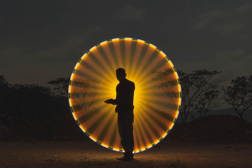 Asian people standing in front of light yellow circle against a dark background