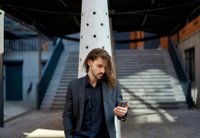 man in black suit using smartphone on the street