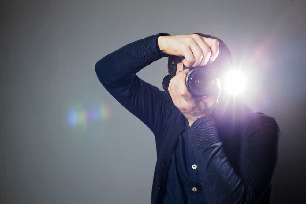 man takes a picture on a camera with built-in flash