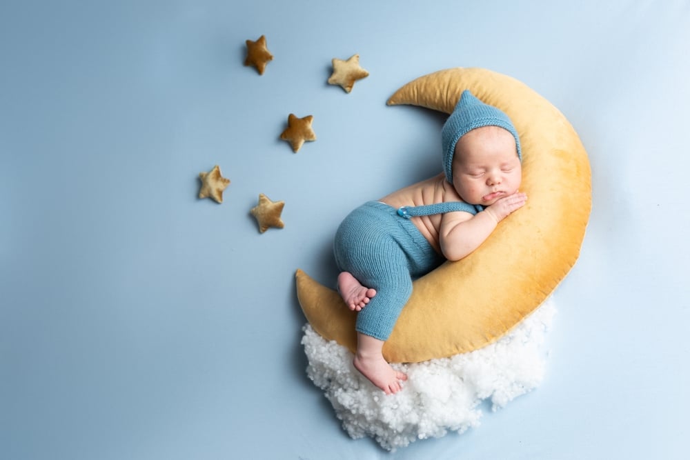 newborn baby lies on the moon on a blue background