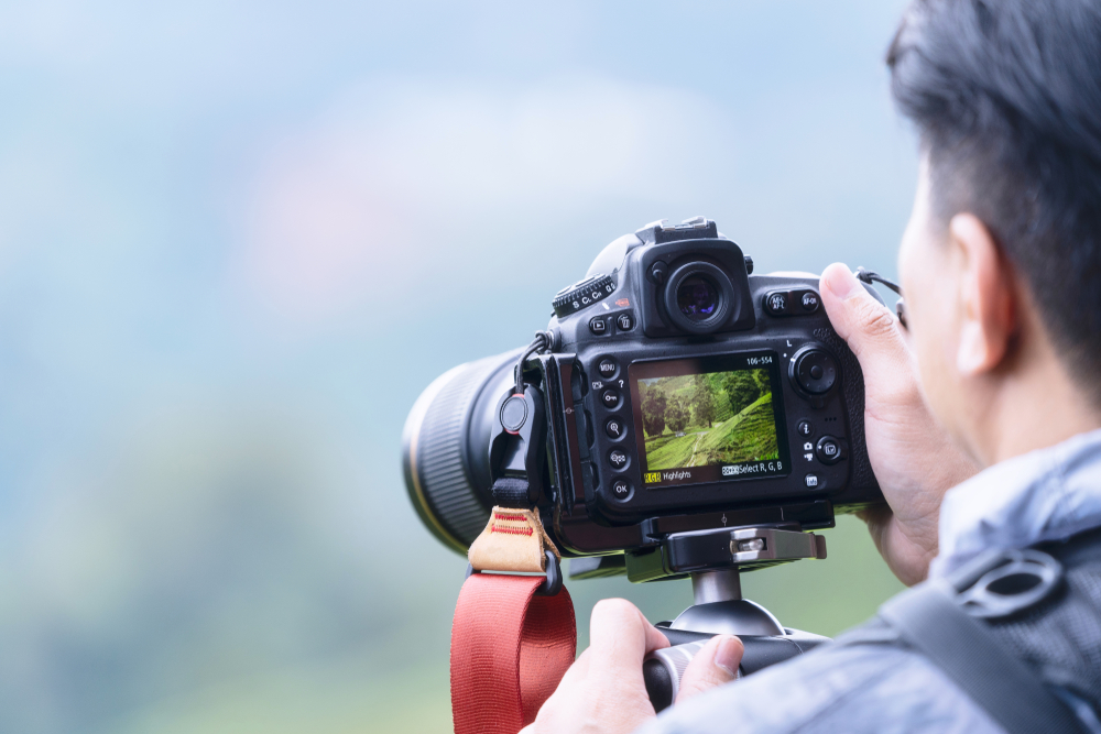 photographer using a DSLR camera to take landscape photo