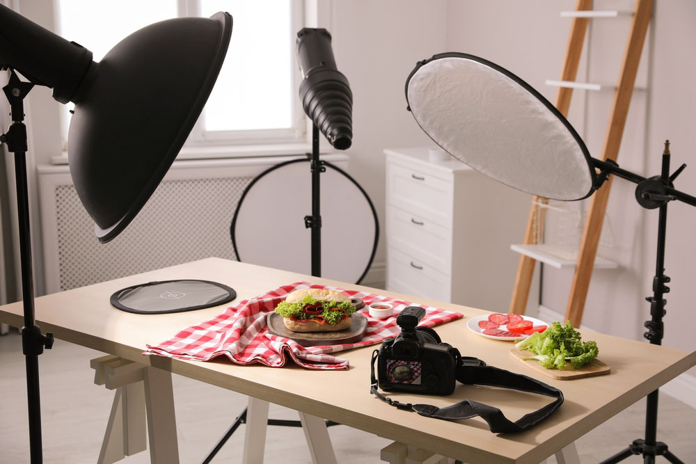 sandwich and vegetables on table with photography gear