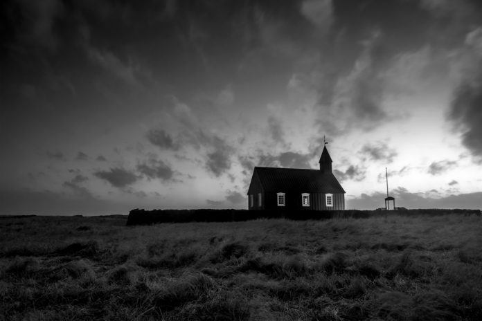 An old church in a remote countryside in Iceland during a rainy, stormy evening