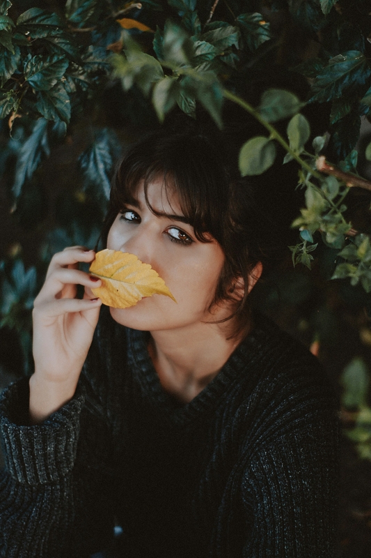 Woman holding a leaf over her mouth