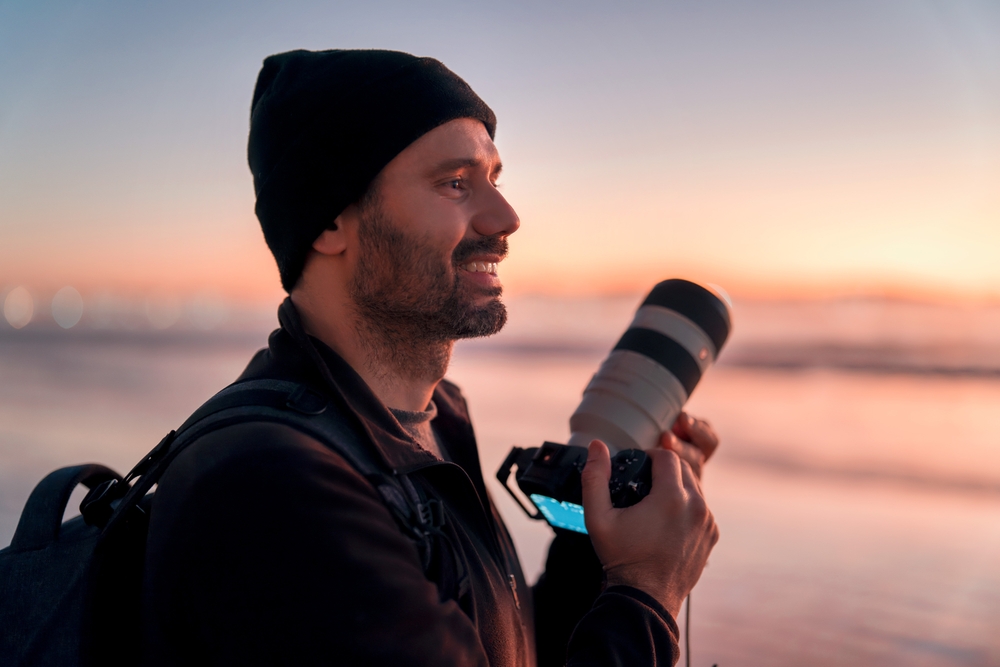 photographer holding professional camera on the beach 