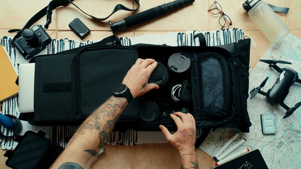 photographer packs backpack camera bag with photo gear