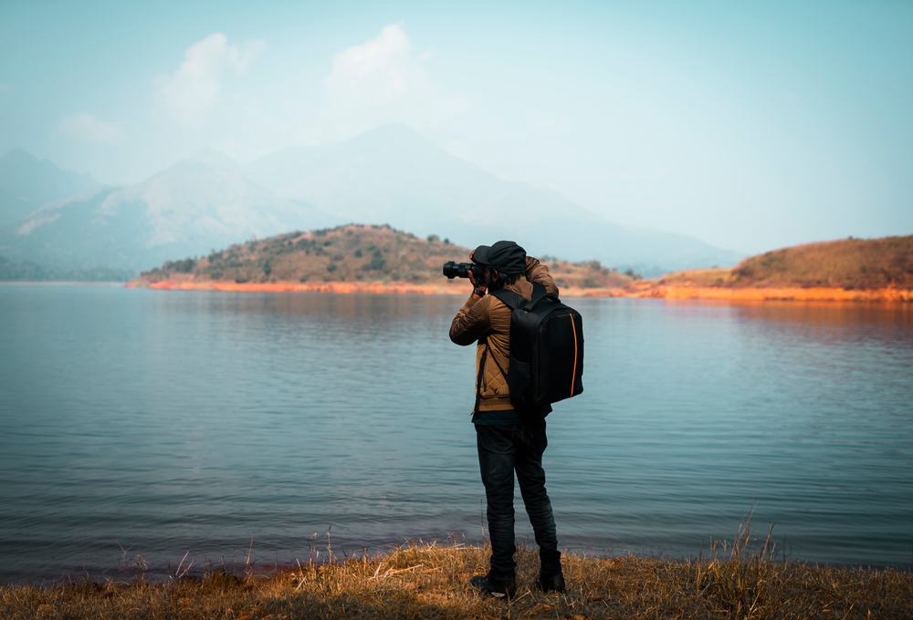 photographer with camera and backpack at a mountain lake