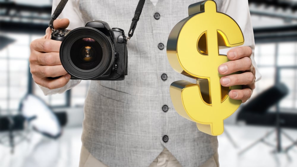 photographer with digital camera and dollar sign